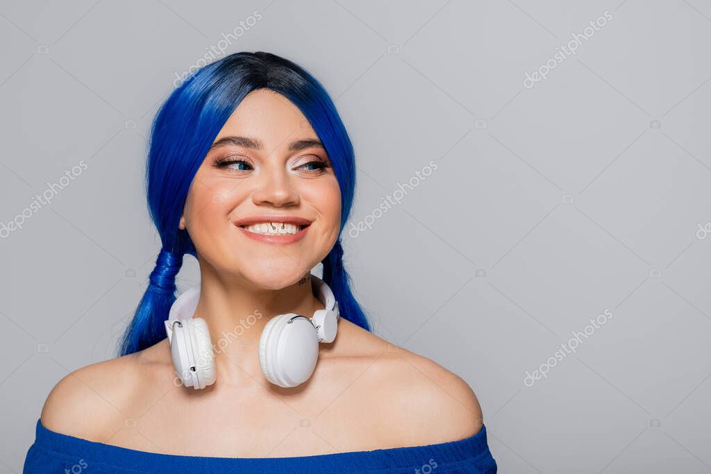 music lover, smiling young woman with blue hair and wireless headphones smiling on grey background, vibrant youth, individualism, modern subculture, self expression, tattoo, sound