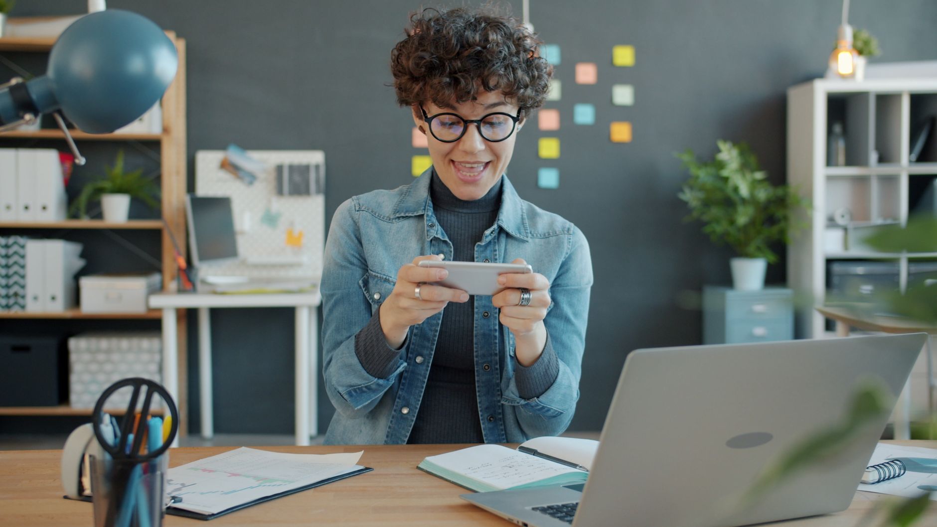 happy professional woman engaging with smartphone in office